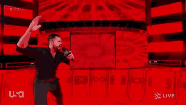 a man in a black shirt is holding a microphone in front of a red background ..