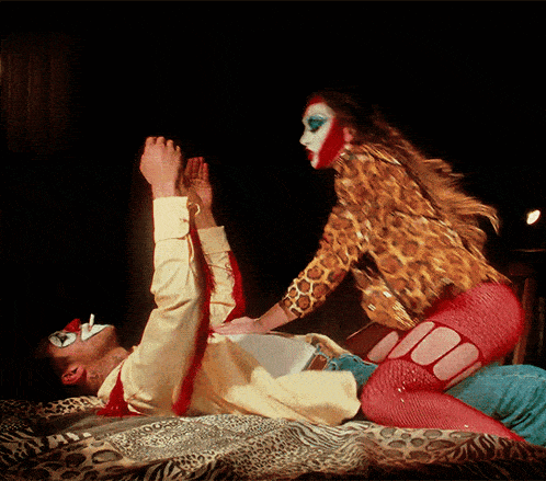 a woman in a leopard print outfit is kneeling on a man