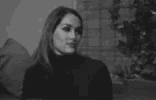 a woman is sitting on a couch in a black and white photo looking at the camera .