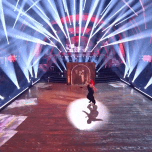 a couple dancing on a stage with a lot of lights behind them