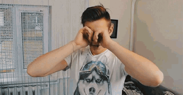 a young boy wearing a white t-shirt with a picture of a husky on it is yawning .