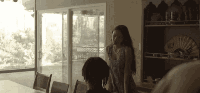 a woman in a blue dress is standing next to a man in a black shirt in a living room .