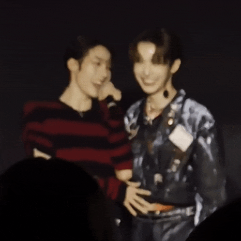 a blurry picture of two men standing next to each other in a dark room .