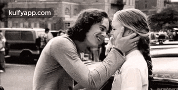a man and a woman are kissing on the street .