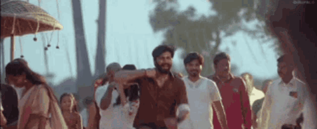 a group of people are walking down a street and a man is carrying a woman on his shoulders .