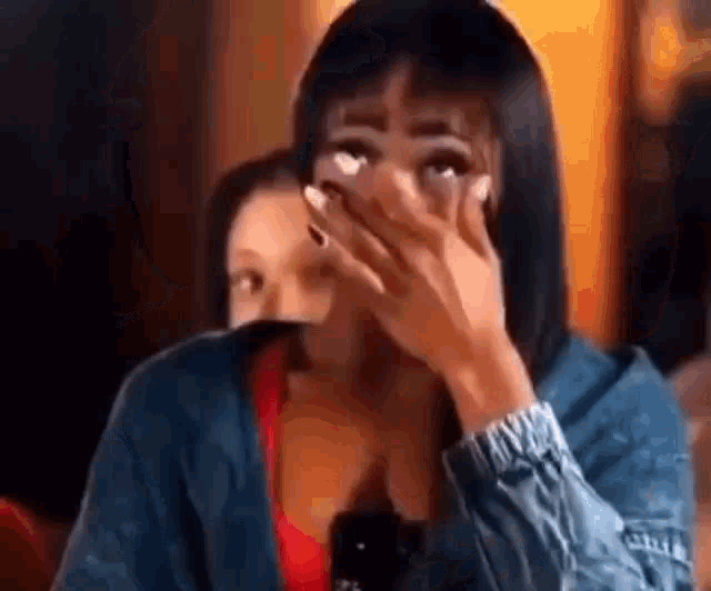 a woman is covering her face with her hand while sitting at a table in a restaurant .