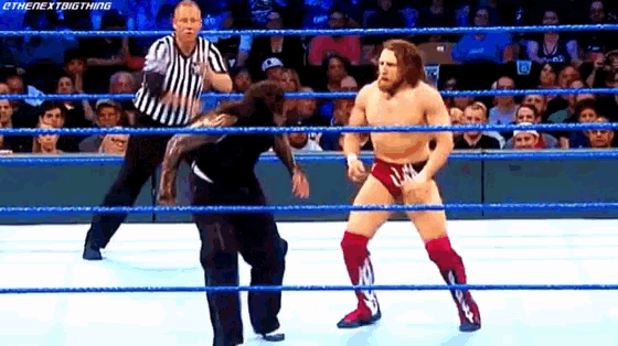 a wrestler is standing in a wrestling ring while a referee watches .
