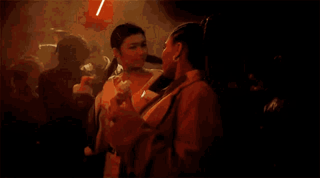two women are kissing each other in a dark room while dancing .