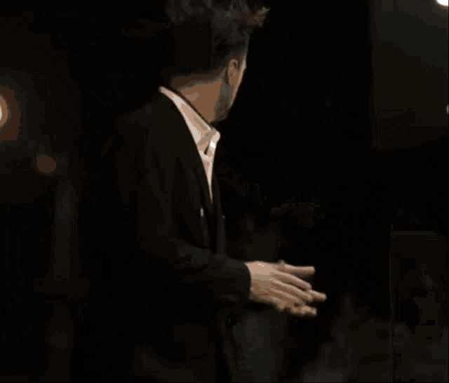 a man in a suit is covering his face with his hand .