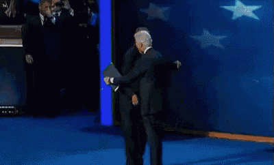 a man in a suit and tie is talking to another man in a suit and tie on a stage .