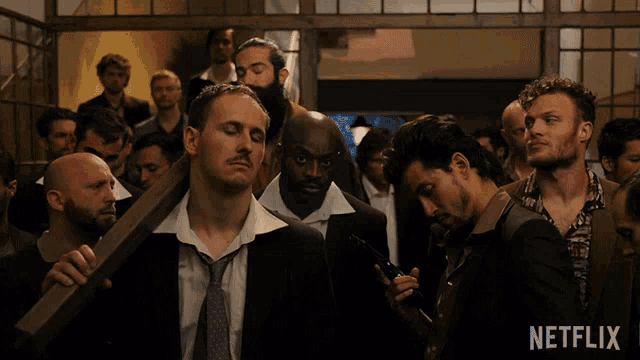 a group of men standing in a room with a netflix logo in the corner