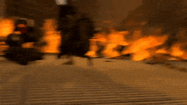a blurred image of a person running in front of a fire .