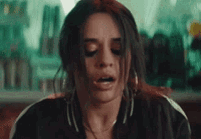a close up of a woman making a funny face while wearing a black jacket and earrings .