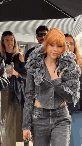 a woman with red hair is wearing a grey jacket