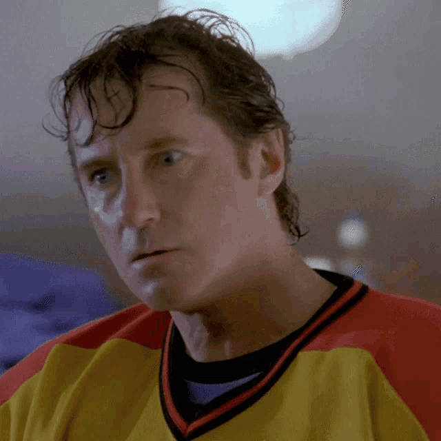 a man with wet hair wearing a yellow and red jersey