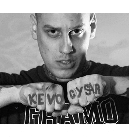 a black and white photo of a man with a tattoo on his fingers that says kevo gysr