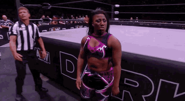 a woman in a wrestling ring with a referee standing behind her