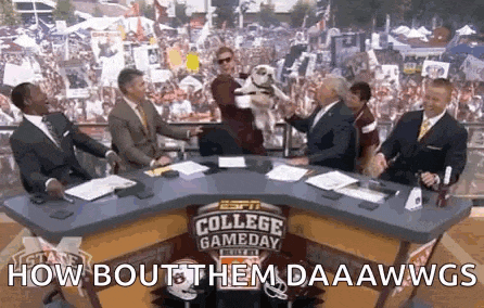 a group of men are sitting at a table with a dog on it and the words `` how bout them daaawwgs '' .