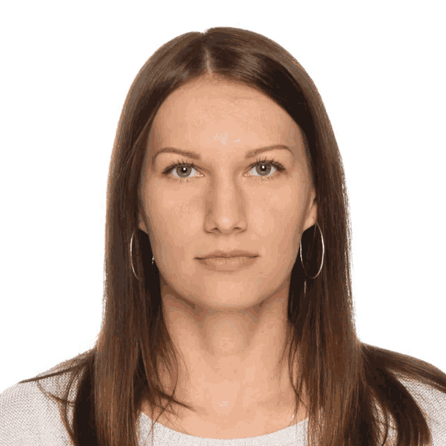 a woman wearing hoop earrings and a white shirt looks at the camera