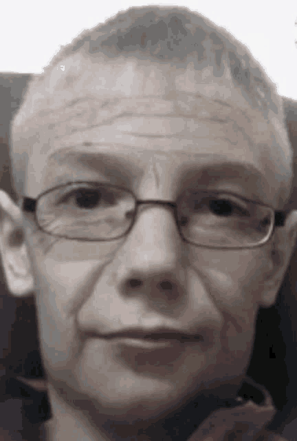 a close up of a man 's face with glasses and a bald head .