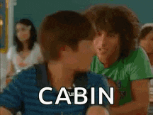 a girl is sitting at a desk in a classroom with the word cabin on her shirt .