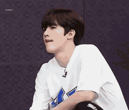 a young man wearing a white t-shirt with a blue x on it