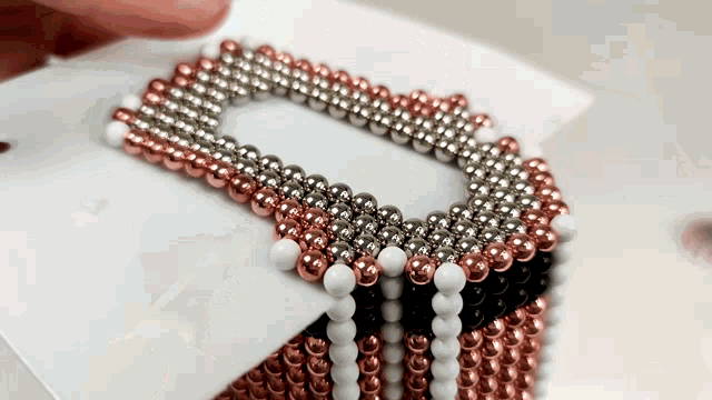 a person is holding a bracelet made of copper and silver beads