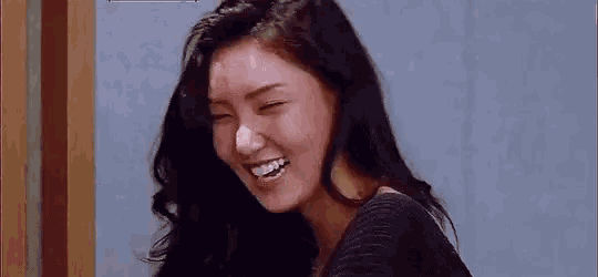 a close up of a woman laughing with her eyes closed and her mouth open .