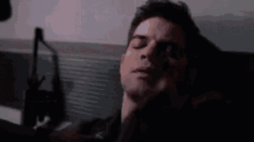 a man is laying on a bed with his eyes closed and his hand on his chin .