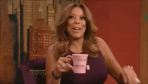 a woman is holding a pink wendy mug