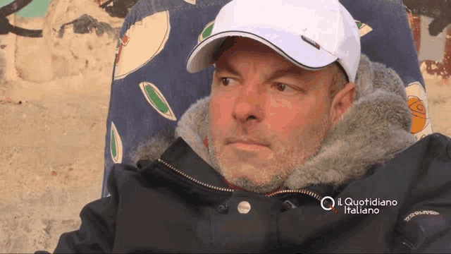 a man wearing a white hat and a black jacket with il quotidiano italiano written on it