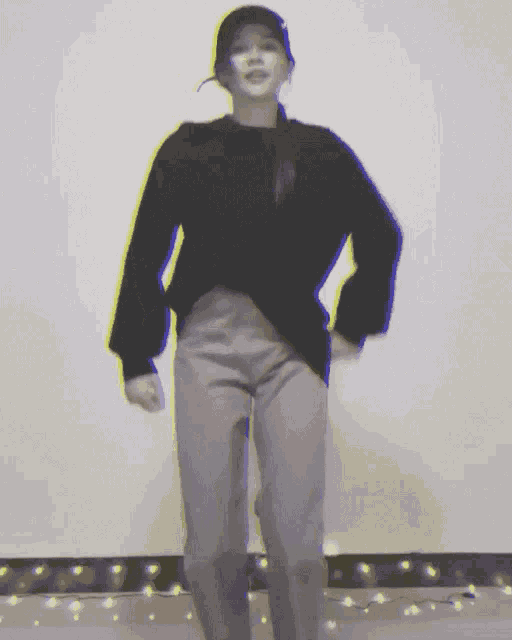 a woman in a black sweater and grey pants dancing
