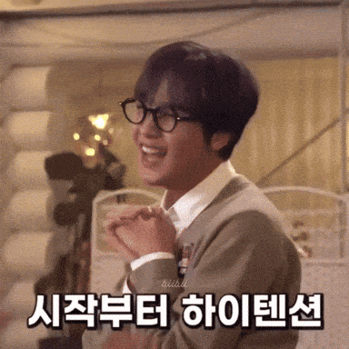 a young man wearing glasses is making a heart shape with his hands .