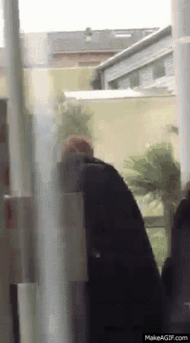 a person standing in front of a window with a makeagif.com link