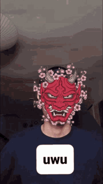 a man wearing a red demon mask with flowers around his face and a uwu button