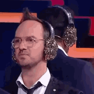 a man in a suit and tie wearing headphones and glasses .