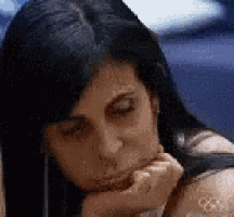 a woman with long black hair is sitting with her head resting on her hand .