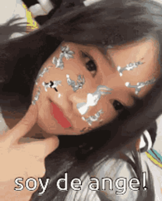 a girl with stickers on her face and the words soy de angel