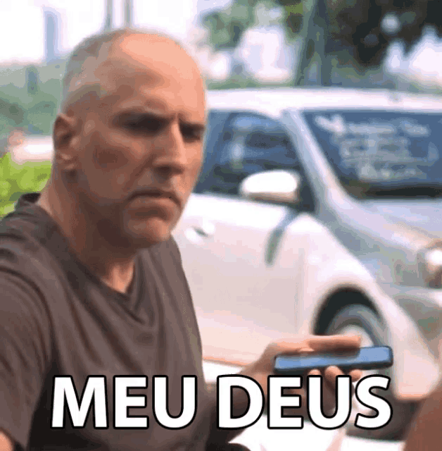 a man holding a cell phone with the words meu deus on the bottom