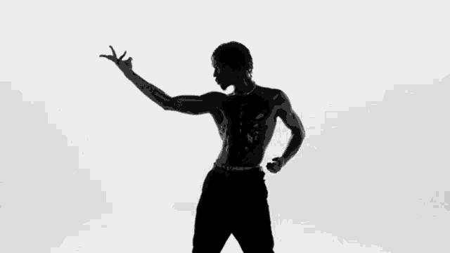 a silhouette of a man without a shirt is dancing in front of a white background .