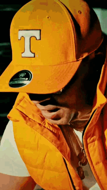a man wearing a yellow hat with a white letter t on it