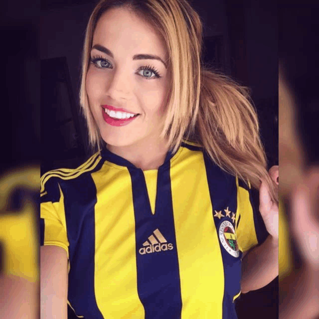 a woman wearing a yellow and blue striped adidas shirt