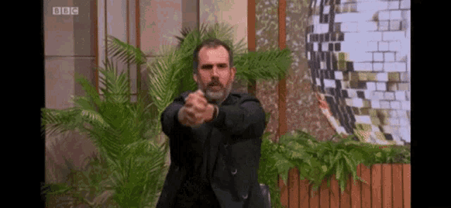 a man in a suit is pointing his gun at the camera .
