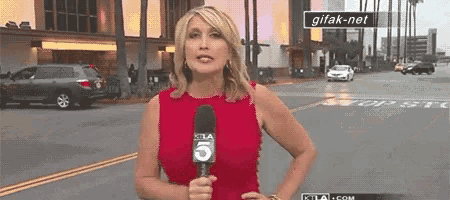 a woman in a red dress is holding a microphone with the number five on it