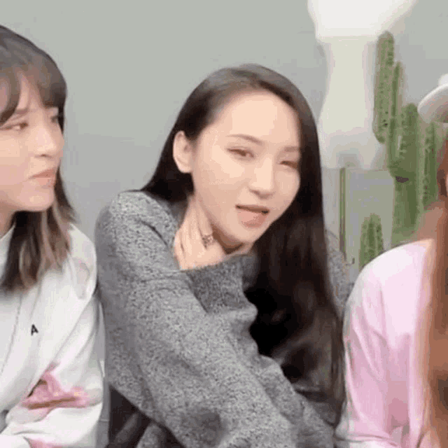 a group of women are sitting next to each other in a room and one of them is making a funny face .