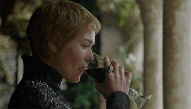 a woman drinking a glass of wine with a ring on her hand