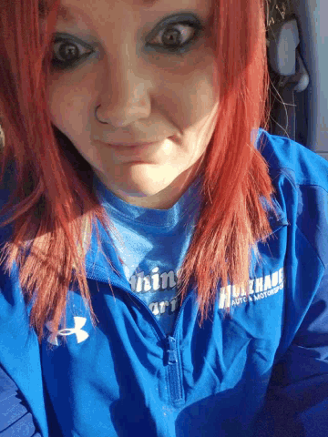 a woman with red hair is wearing a blue shirt that says ' faith '