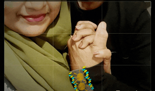 a woman in a green scarf holds a man 's hand in a photo