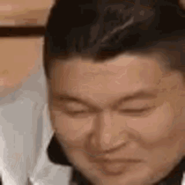 a man with his eyes closed is making a funny face .