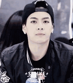 a young man wearing a black baseball cap and a black jacket .